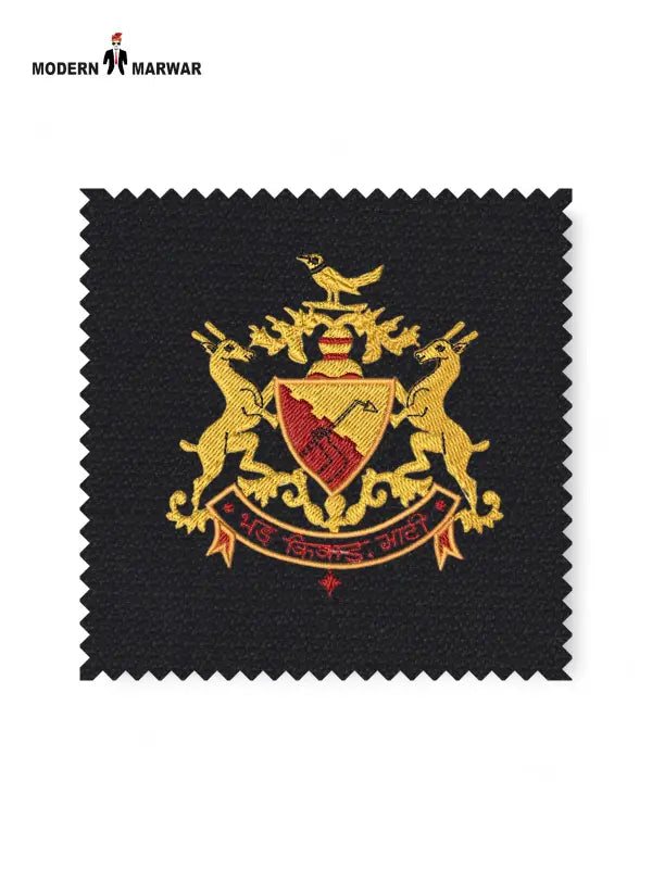 Detailed fabric swatch of Bhati Coat Suit for Men featuring a gold embroidered emblem on black background