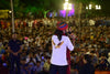 Man performing on stage wearing an eagle logo shirt, large crowd enjoying the event