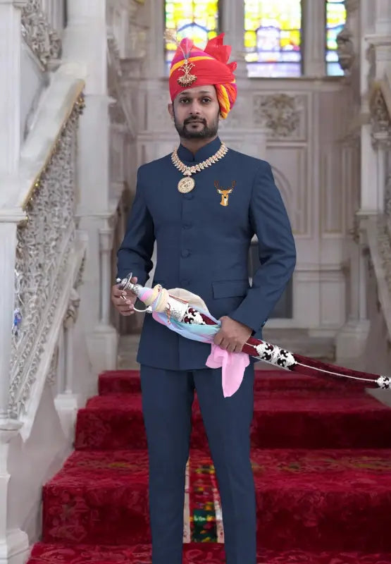 Embroidered deer logo coat suit in navy worn by a man holding a traditional weapon in an ornate setting