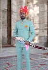 Man in a light blue Jodhpuri suit featuring an embroidered logo Jodhpuri and a decorative sword