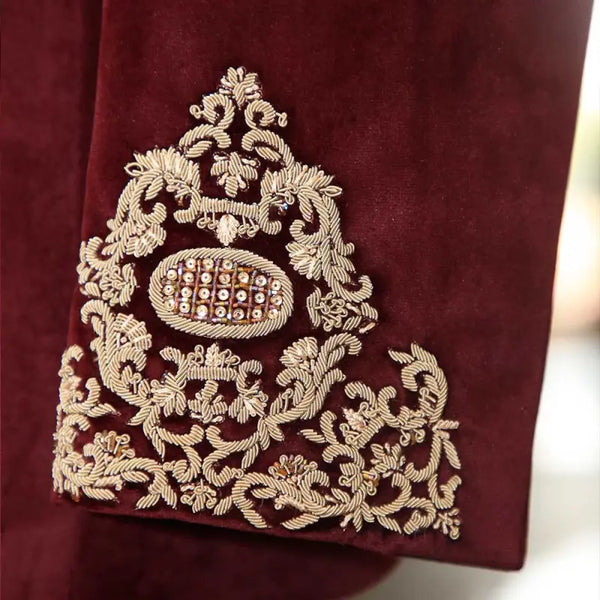 Close-up of exclusive men's designer coat featuring intricate gold embroidery on burgundy fabric
