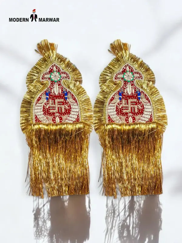 Gold epaulette accessories with intricate design and fringed edges for traditional attire.