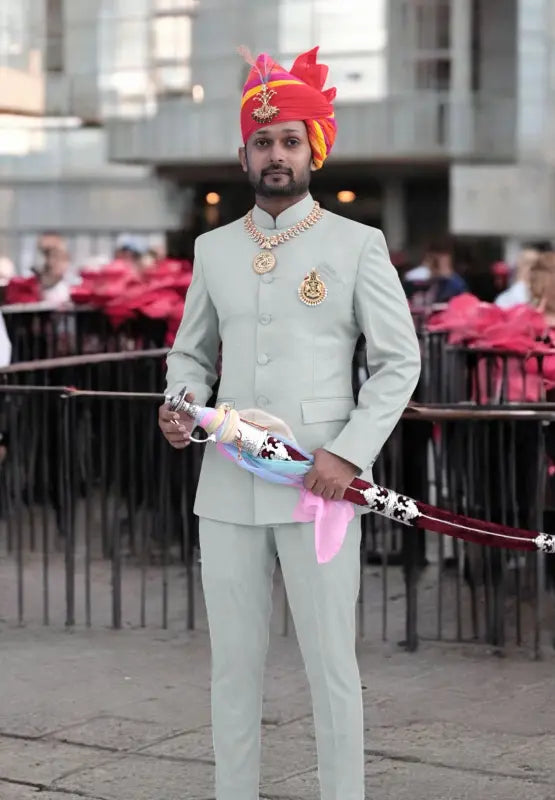 Elegant Jodhpuri suit for men in light green with traditional accessories and a colorful turban