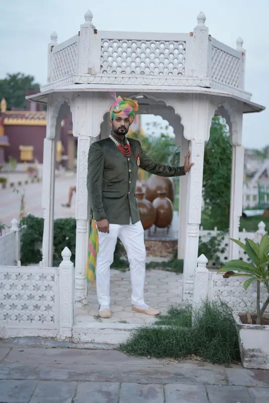 Stylish men's wedding coat suit in green worn in an outdoor setting with traditional accessories