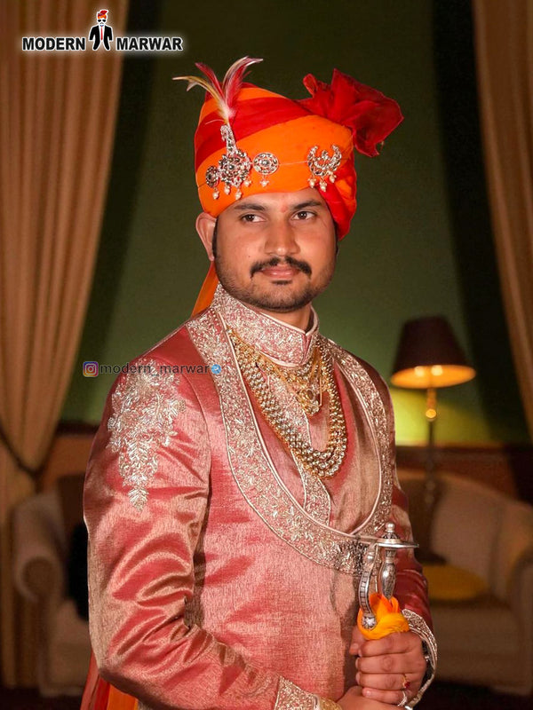 Elegant designer angarkha sherwani for men in peach with traditional accessories and bright orange turban