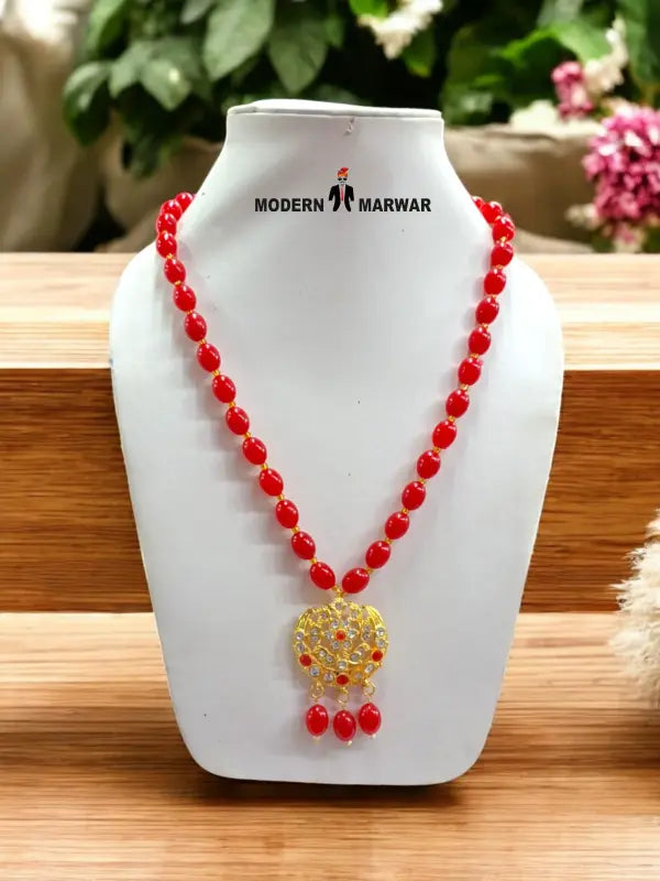 Red beaded necklace with a golden pendant featuring intricate design details
