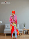 A vibrant traditional Indian wedding sherwani in pink and green, styled with colorful accessories