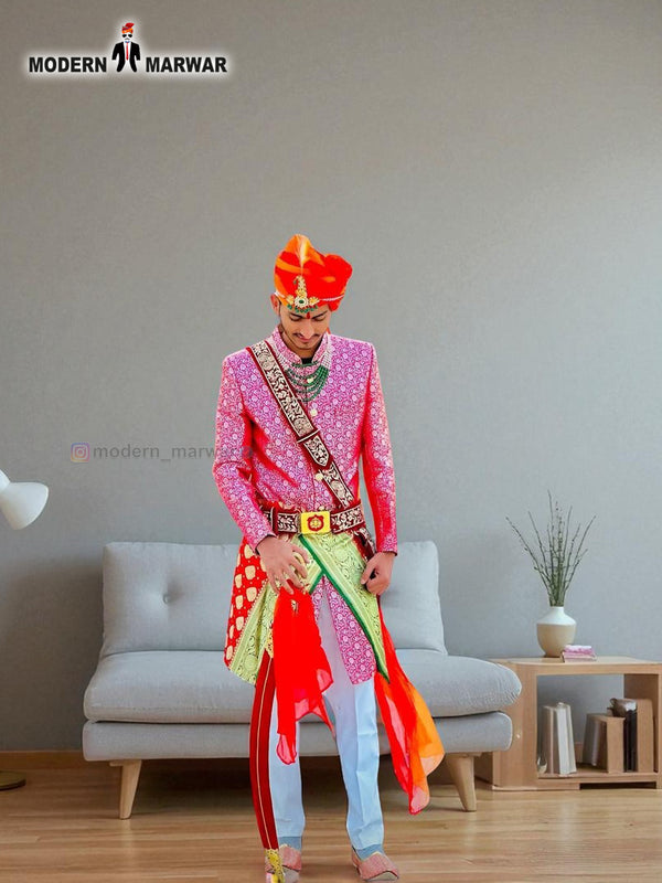 A vibrant traditional Indian wedding sherwani in pink and green, styled with colorful accessories