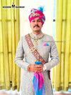 Elegant wedding groom sherwani in beige with intricate designs and colorful accessories