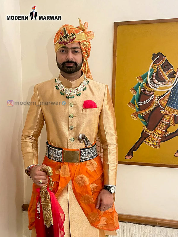 Elegant wedding groom sherwani in gold with intricate details and vibrant orange turban