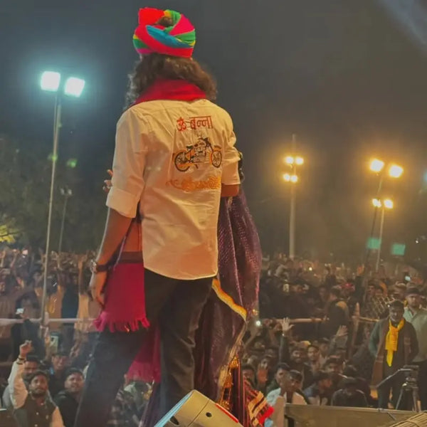 Man wearing Modern Marwar Om Banna logo shirt with colorful turban at an outdoor night event