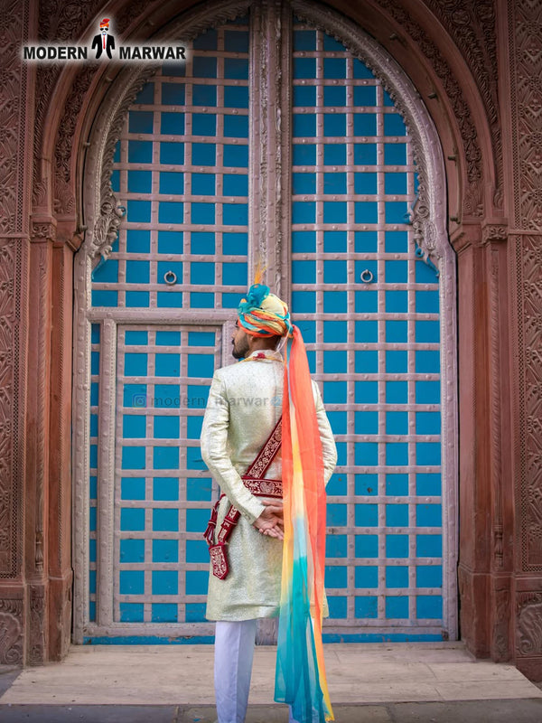 Elegant wedding groom sherwani with vibrant turban displayed against a historic backdrop