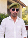 Default Coffee Beret Cap Solanki Lobo in green fabric, worn with sunglasses at a side angle