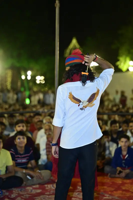 Modern Marwar eagle logo shirt worn by performer at cultural event for a vibrant audience