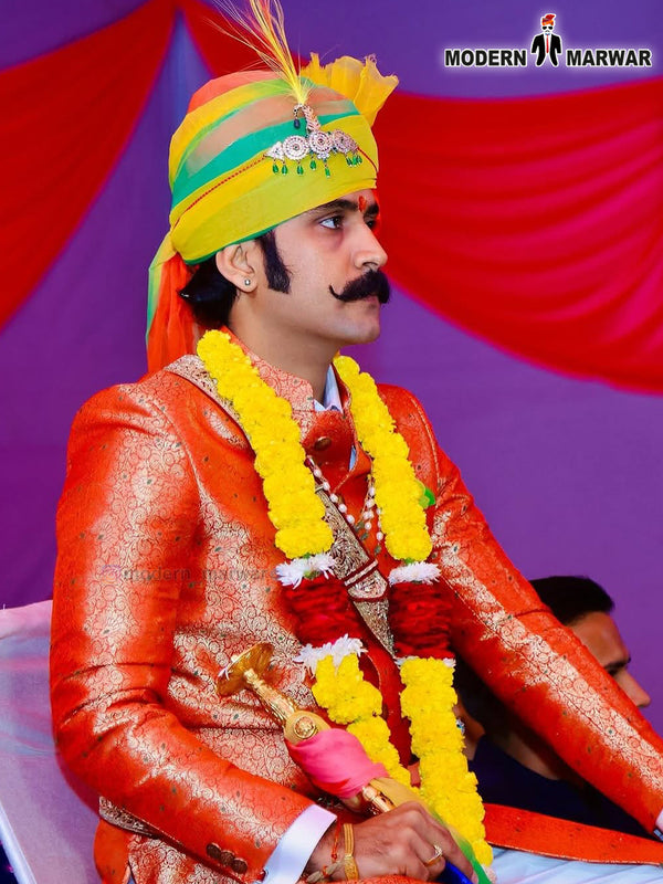 Stylish wedding groom sherwani in orange with traditional ornaments and vibrant floral necklace