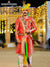 Vibrant wedding groom sherwani with intricate design, worn by a man at a festive outdoor setting