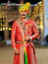 Traditional wedding groom sherwani in vibrant red with intricate designs, styled with a colorful turban
