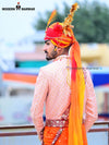Stylish wedding groom sherwani in peach with intricate designs and bright accessories