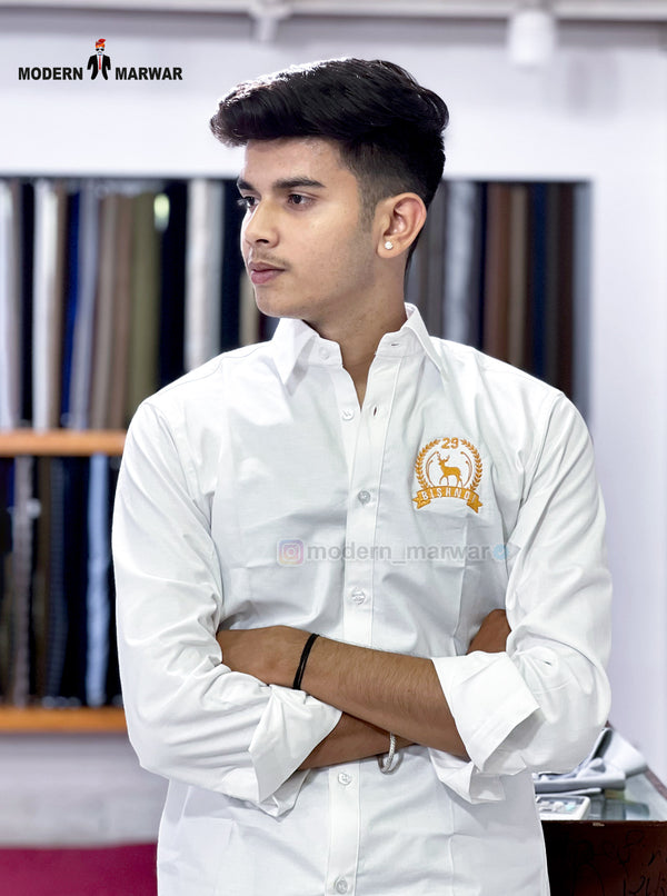 Bishnoi logo shirt white by SINGH worn by model with folded arms in a fabric store background