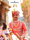 Elegant man in Premium Angarkha sherwani, adorned with traditional jewelry, riding a horse in a historic setting