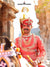 Elegant man in Premium Angarkha sherwani, adorned with traditional jewelry, riding a horse in a historic setting