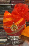 Men's Rajasthani safa in vibrant red and orange colors adorned with decorative jewelry