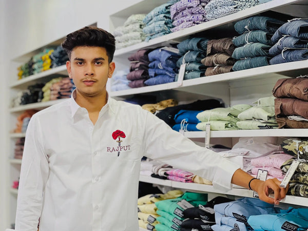 Man wearing white men's Rajput design shirt standing in front of shelves with folded clothes