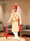 Elegant wedding groom sherwani in cream with intricate embroidery and red accessories